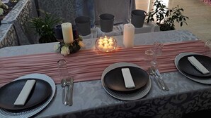 A table set with black plates, clear glasses, and silverware, decorated with candles and a pink runner. - Jate Guest House (Maseru)
