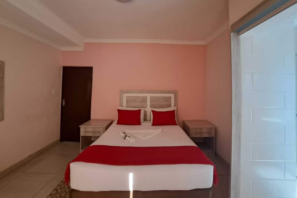 A bedroom with a bed, two bedside tables, a door, and a ceiling light.
