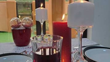 Una mesa lista para una comida, con velas, una copa de vino tinto y cristalería decorativa.