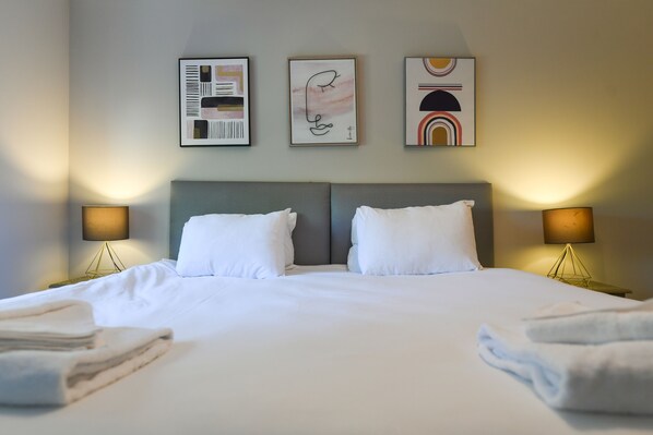 Relax in comfort with a large bed, wall-mounted lamps, and artwork above.