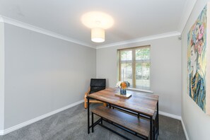 Cozy dining area with a wooden table, leather chair, and vase with flowers.