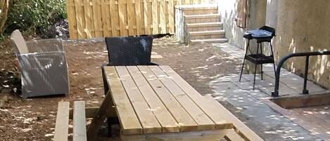 Patio esterno con tavolo di legno e due sedie in vimini.