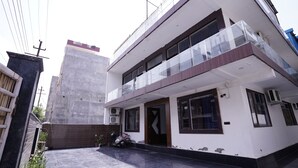 Una casa moderna de dos plantas con un balcón, un garaje y una motocicleta estacionada afuera.