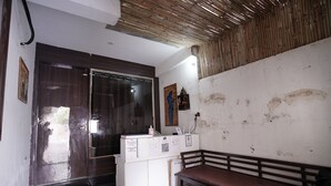 Un área de recepción con un banco de madera, un mostrador de recepción con una computadora y una pared con un mural.