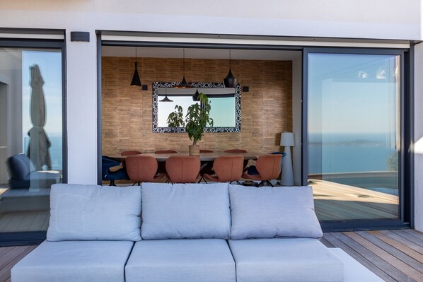 Ein modernes Wohnzimmer mit einer Couch, einem Essbereich mit Tisch und Stühlen und einem großen Fenster mit Blick.