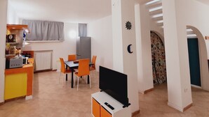 A compact living space with a dining area, kitchenette, and a TV in the center. - Family apartment: sleeps 6, Use of garden, sunbeds and swimming pool. (Monte San Pietro)
