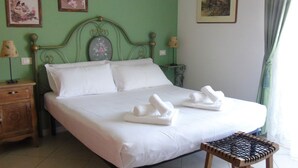 A neatly made bed with white linens and towels, a wooden nightstand with a lamp, and a small wooden stool. - Homiday - B&B Meraviglie d'Abruzzo (Cellino Attanasio)