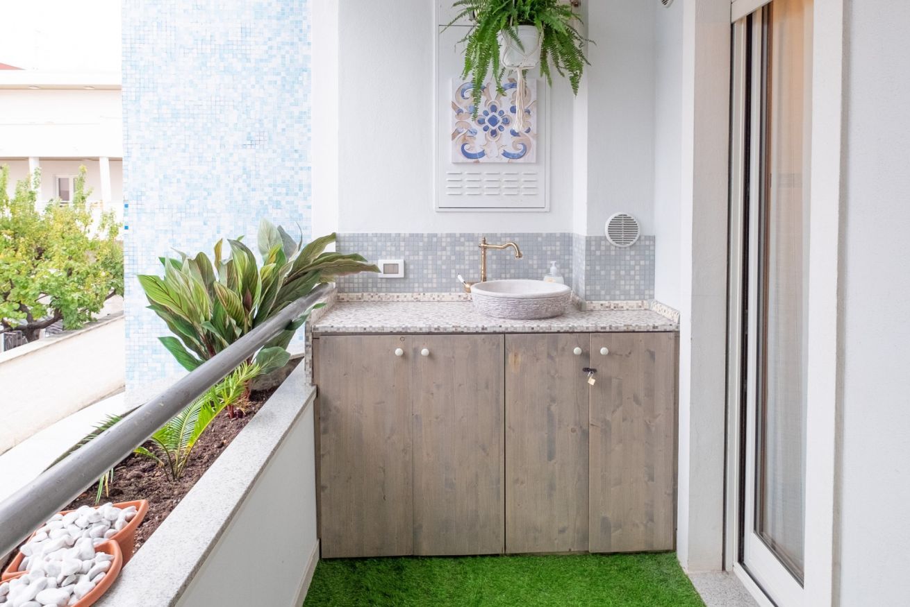 Een kleine badkamer met een houten wastafelmeubel, een wastafel en een plant in pot.