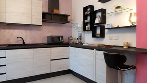 A modern kitchen with white cabinetry, black countertops, and a black chair. - Homiday - B&B Meraviglie d'Abruzzo (Cellino Attanasio)