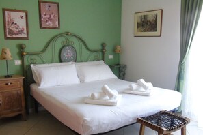 A neatly made bed with white linens and two towels folded on top, a wooden nightstand with a lamp, and a small wooden stool. - Homiday - B&B Meraviglie d'Abruzzo (Cellino Attanasio)