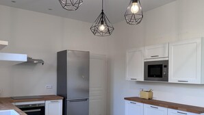 Eine moderne Küche mit einem Edelstahl-Kühlschrank, weißen Schränken, einer Mikrowelle und Holz Arbeitsplatten.