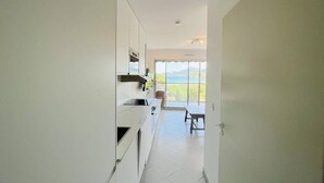 Eine moderne Küche mit weißen Schränken und Blick auf einen Balkon.