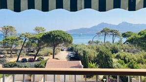 Ein Balkon mit Blick auf eine Küstenstraße, parkende Autos und Bäume.