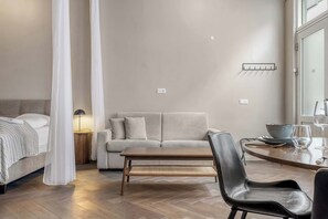 Ein modernes Schlafzimmer mit einem Bett, einer Couch, einem Esstisch und einem Sessel.