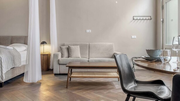 A modern bedroom with a bed, a sofa, a dining table, and a chair. - Swan Deluxe Studio for 4 guests (Reykjavík)