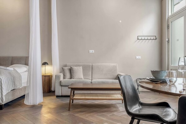 A modern bedroom with a bed, a sofa, a dining table, and a chair.