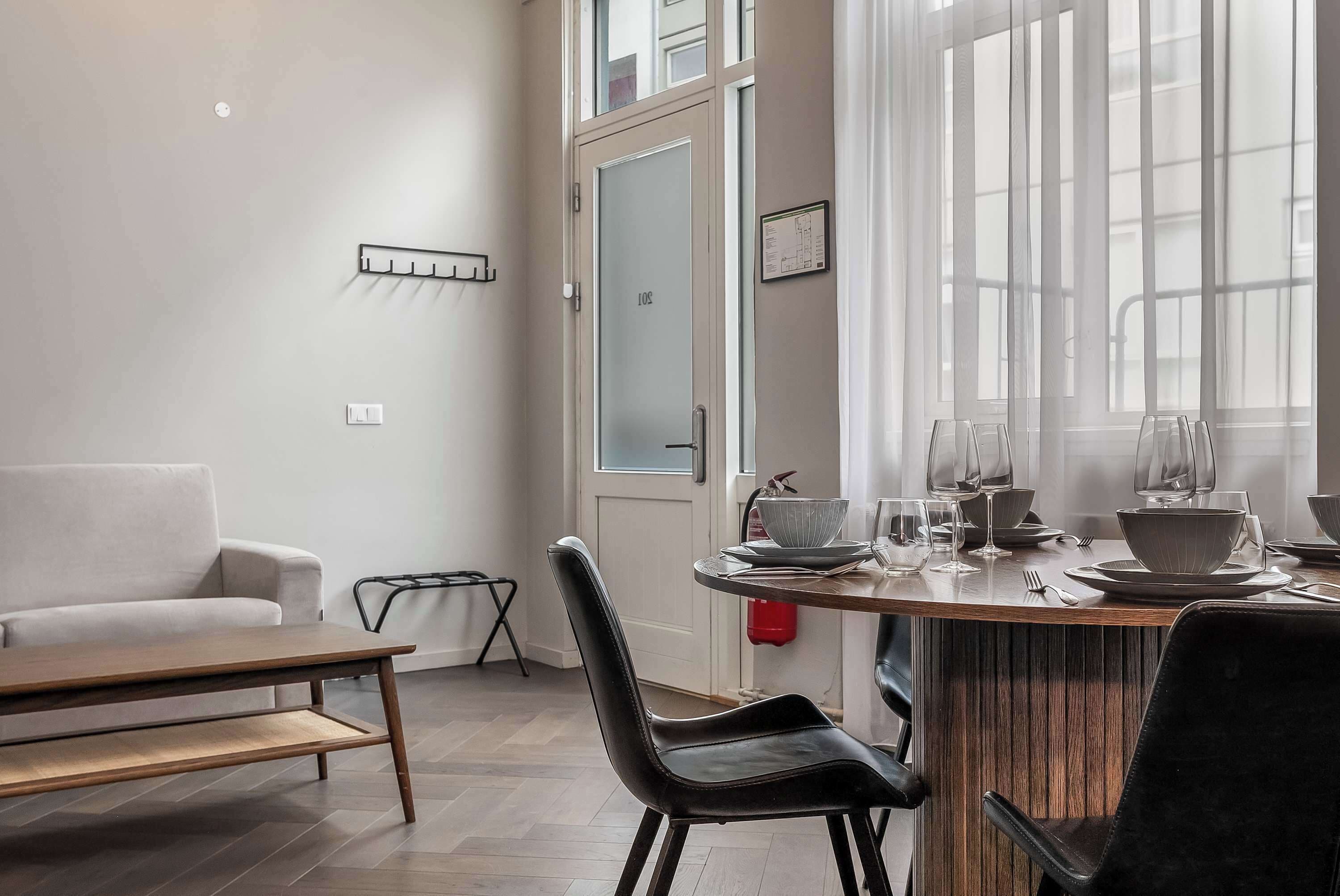 A modern dining area with a wooden table, black chairs, and a white sofa.