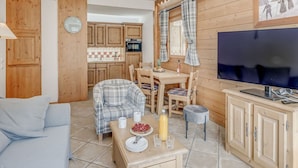 Ein gemütliches Wohnzimmer mit einer Couch, einem Esstisch mit Stühlen, einem Fernseher und Holzschränken.