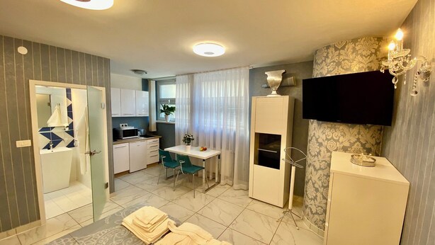 Une chambre d’hôtel avec salle de bain, une petite kitchenette, un coin repas et un téléviseur fixé au mur.