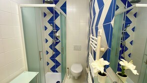 Une salle de bain équipée d’une douche, de toilettes et d’un lavabo avec un miroir.