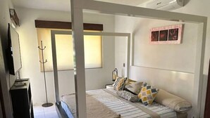 Une chambre à coucher avec un lit, une table de chevet, une lampe et un cadre photo fixé au mur.
