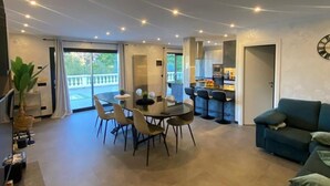 A spacious living area with a dining table and chairs, a sofa, and a kitchen area visible through an open door. - Villa Isabella: relaxation, calm, pool and beautiful beaches nearby (Ventimiglia)