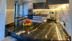 A modern kitchen with a marble countertop, built-in appliances, and bar seating. - Villa Isabella: relaxation, calm, pool and beautiful beaches nearby (Ventimiglia)
