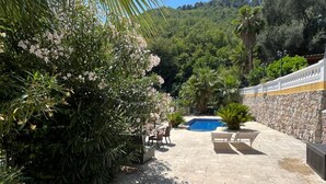A pool area with stone flooring, surrounded by lush greenery and a stone wall. - Villa Isabella: relaxation, calm, pool and beautiful beaches nearby (Ventimiglia)