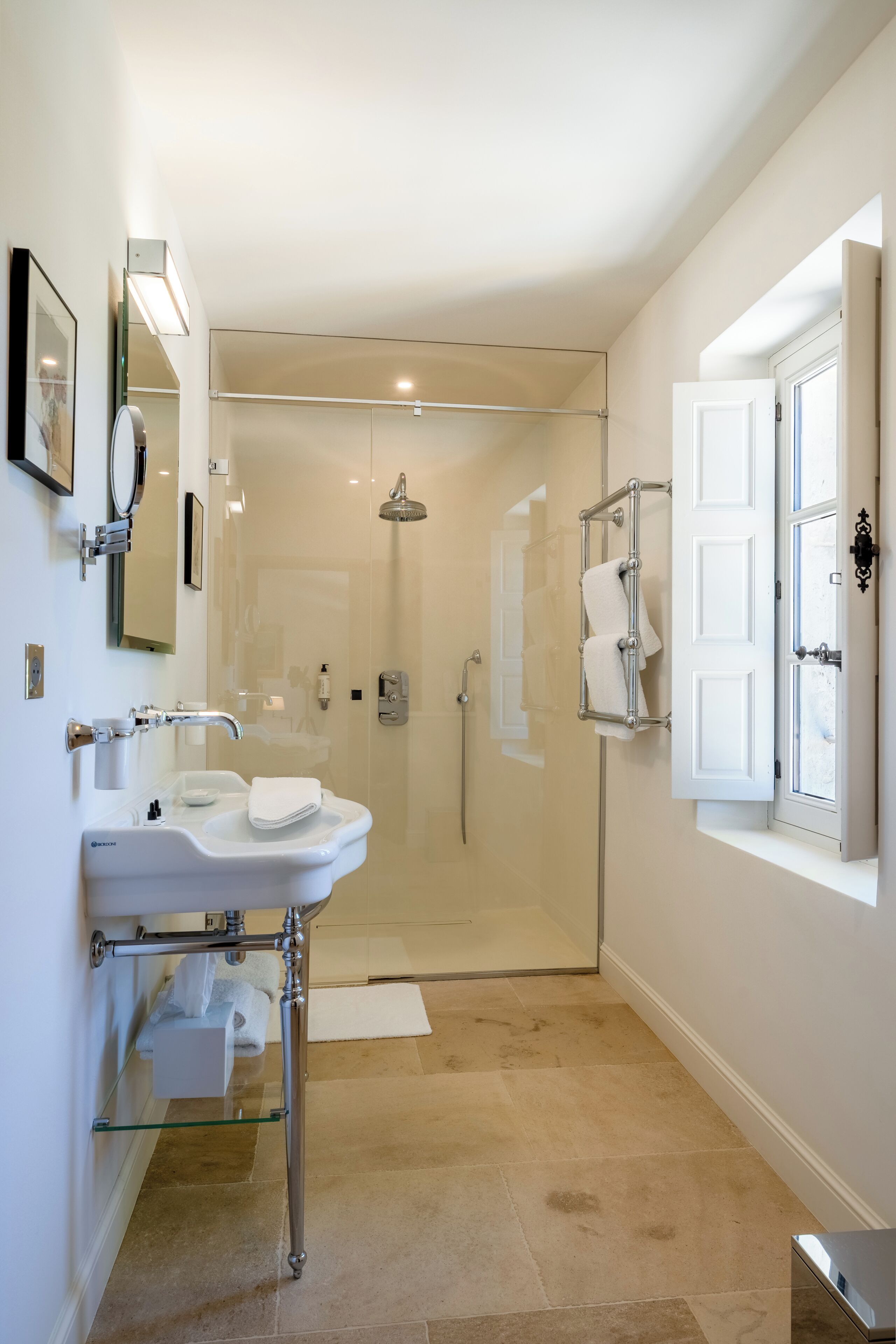 A modern bathroom with a glass shower enclosure, a white sink with chrome fixtures, and a towel rack.