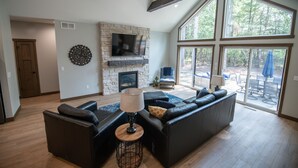 A spacious living room with a stone fireplace, a large flat-screen TV, and a modern sofa set.