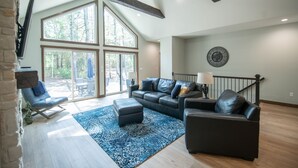 A spacious living room with a large window, a ceiling fan, and a fireplace.