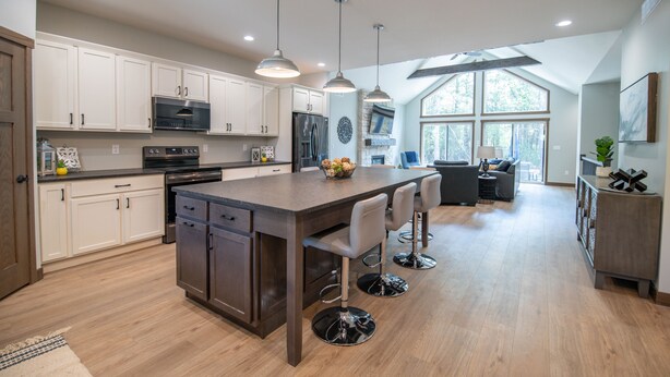 A modern kitchen with white cabinets, stainless steel appliances, and a large island with bar stools.