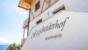 A building with a wooden facade and a sign that reads 'Pegscherhof apartments.'