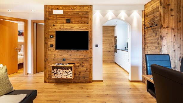 A modern living room with a wooden accent wall, a flat-screen TV, a fireplace, and a cozy seating area.