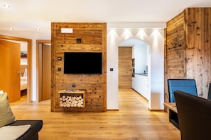 Un salon moderne avec un mur d’accent en bois, un téléviseur à écran plat, une cheminée et un coin salon confortable.