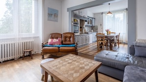 A cozy living room with a sofa, a wooden table, and a dining area with chairs and a table.