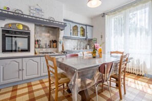 Une cuisine avec une table à manger, des chaises et une fenêtre avec des rideaux.
