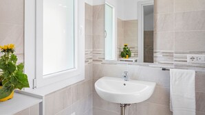 A bathroom with a white sink, a mirror, and a window. - Sardegna è - New rooms (Olbia)