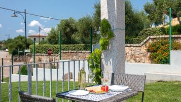 Un área de comedor al aire libre con una mesa para dos, una botella de vino blanco y una copa.