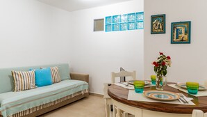 Un salon avec un canapé, une table à manger et des chaises, ainsi qu’une petite fenêtre.