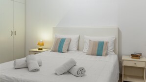 Un lit bien fait, avec des serviettes, une lampe de chevet et une table de nuit sur laquelle sont posés des livres.