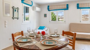 Un coin repas avec une table ronde pour quatre personnes, un canapé et une vue sur l’extérieur.