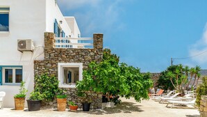Un bâtiment blanc agrémenté de détails en pierre, doté d’un balcon et orné de plantes en pot.