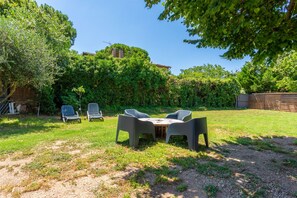 A backyard with a table and chairs, surrounded by greenery and a wooden fence. - 'Rez De Villa' with Private Terrace and Wi-Fi (Le Luc)