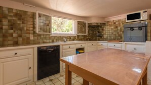 A kitchen with a dishwasher, a microwave, a refrigerator, and a window with a view of greenery.