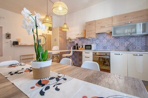 Une cuisine moderne avec des meubles blancs, un four à micro-ondes et un coin repas comprenant une table et des chaises.