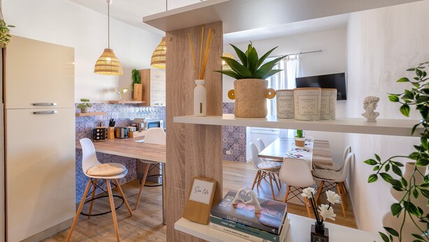 A modern kitchen with a wooden island, pendant lights, and a dining area with white chairs. - Apartment 'Sea Life Holiday Home' with Wi-Fi and Air Conditioning (Alghero)