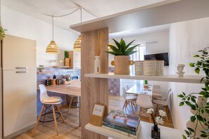 Une cuisine moderne avec un îlot central en bois, des luminaires suspendus et un coin repas avec des chaises blanches.