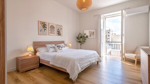 A bedroom with a wooden bed, bedside tables, a hanging light fixture, and a view of the outside balcony. - Apartment 'Sea Life Holiday Home' with Wi-Fi and Air Conditioning (Alghero)