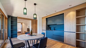 A modern kitchen with wooden cabinets, a dining table with chairs, and pendant lighting. - Apartment 'Huetterhof Langes' with Mountain View, Private Terrace and Wi-Fi (Caines)